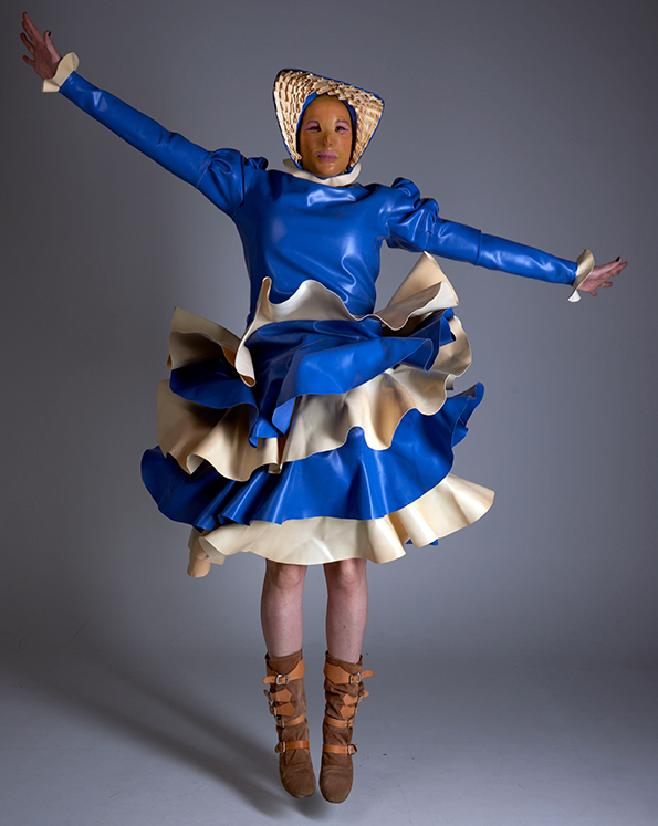 A person in a blue and white latex dress jumping
