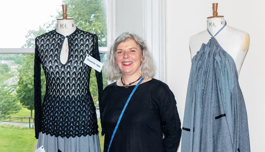 Claire, a woman with grey hair, stood next to two mannequins with dresses on them
