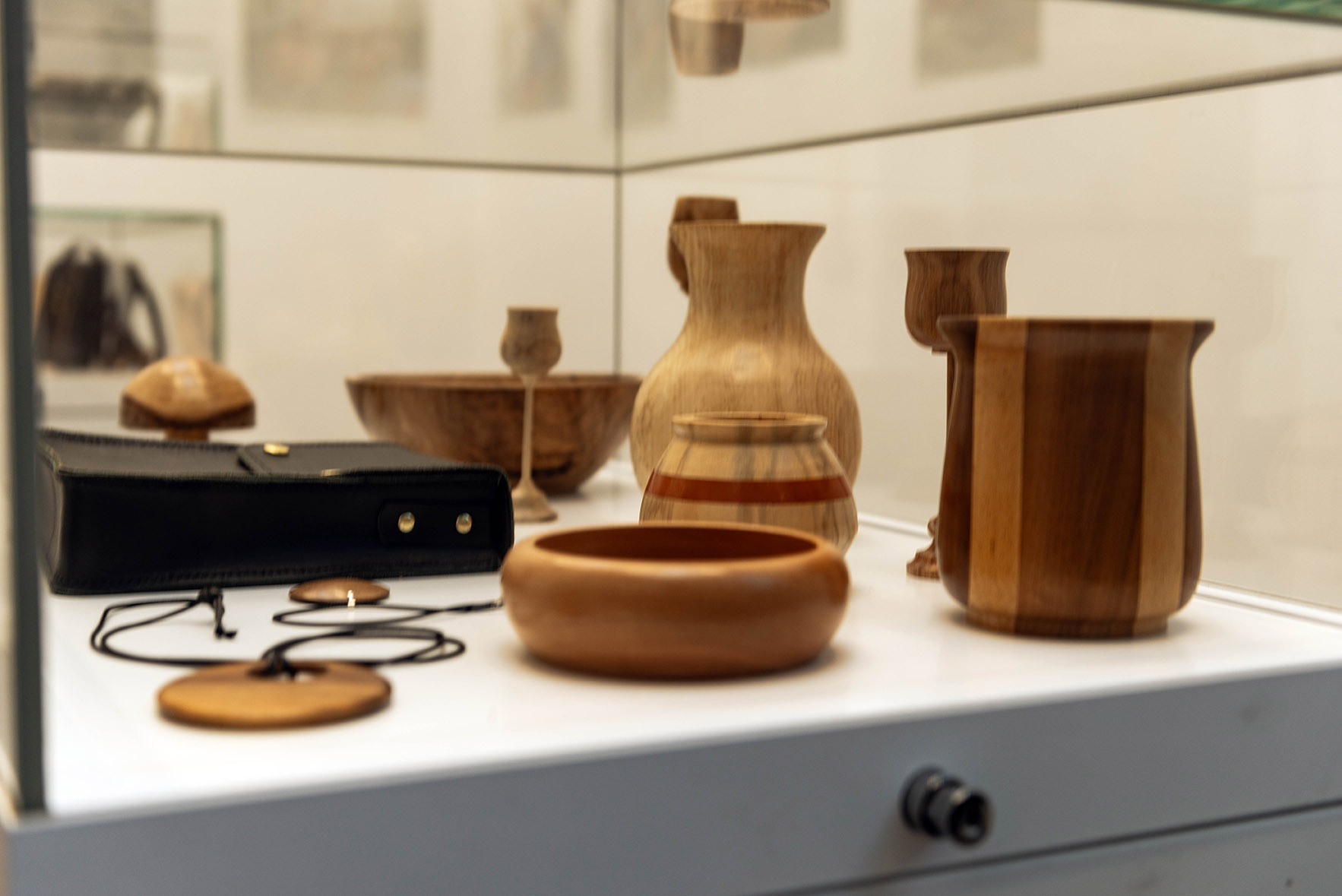 Close up of wooden objects in a glass cabinet.