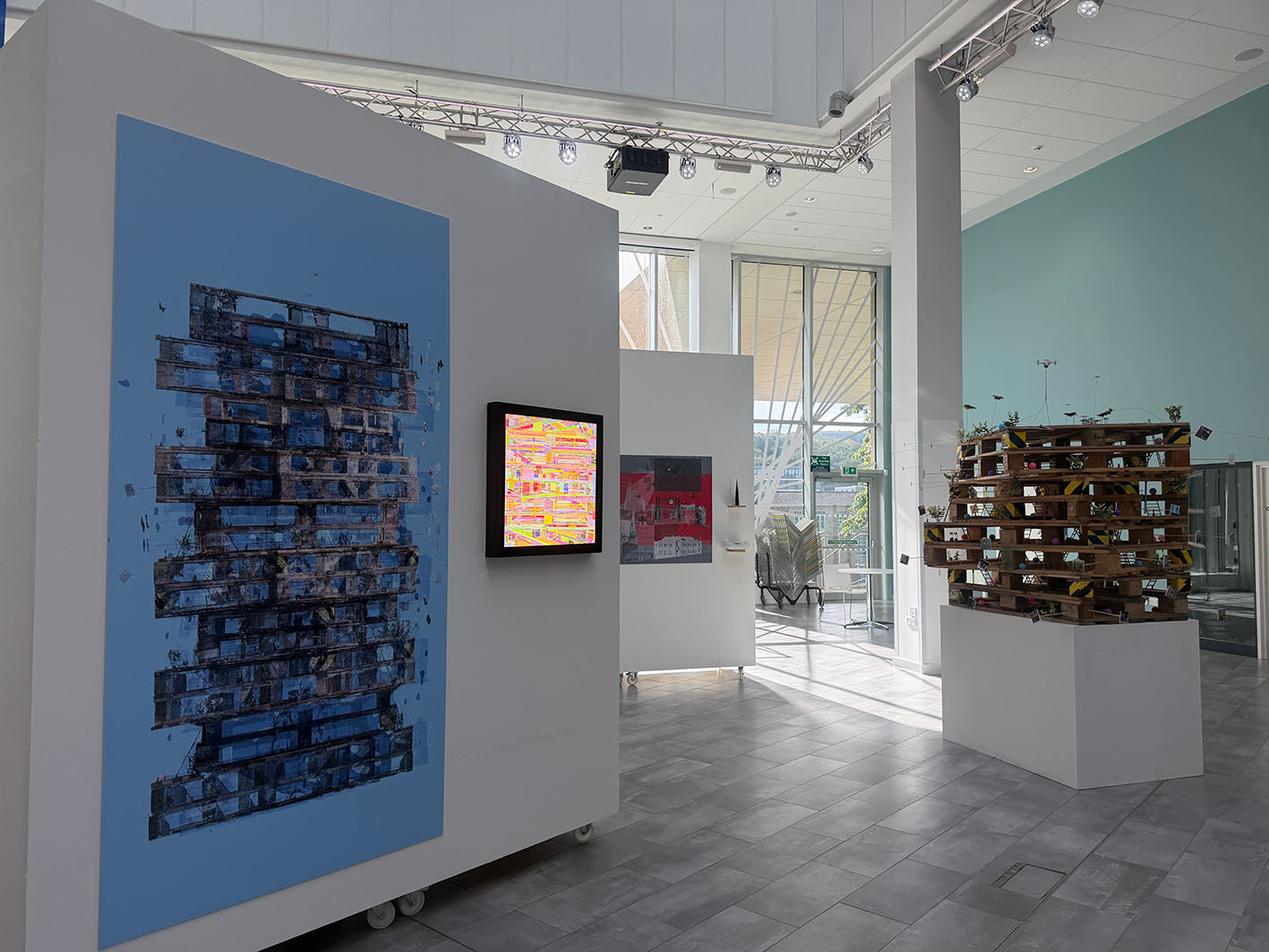 An exhibition showcasing a large printed drawing, sculpture and TV