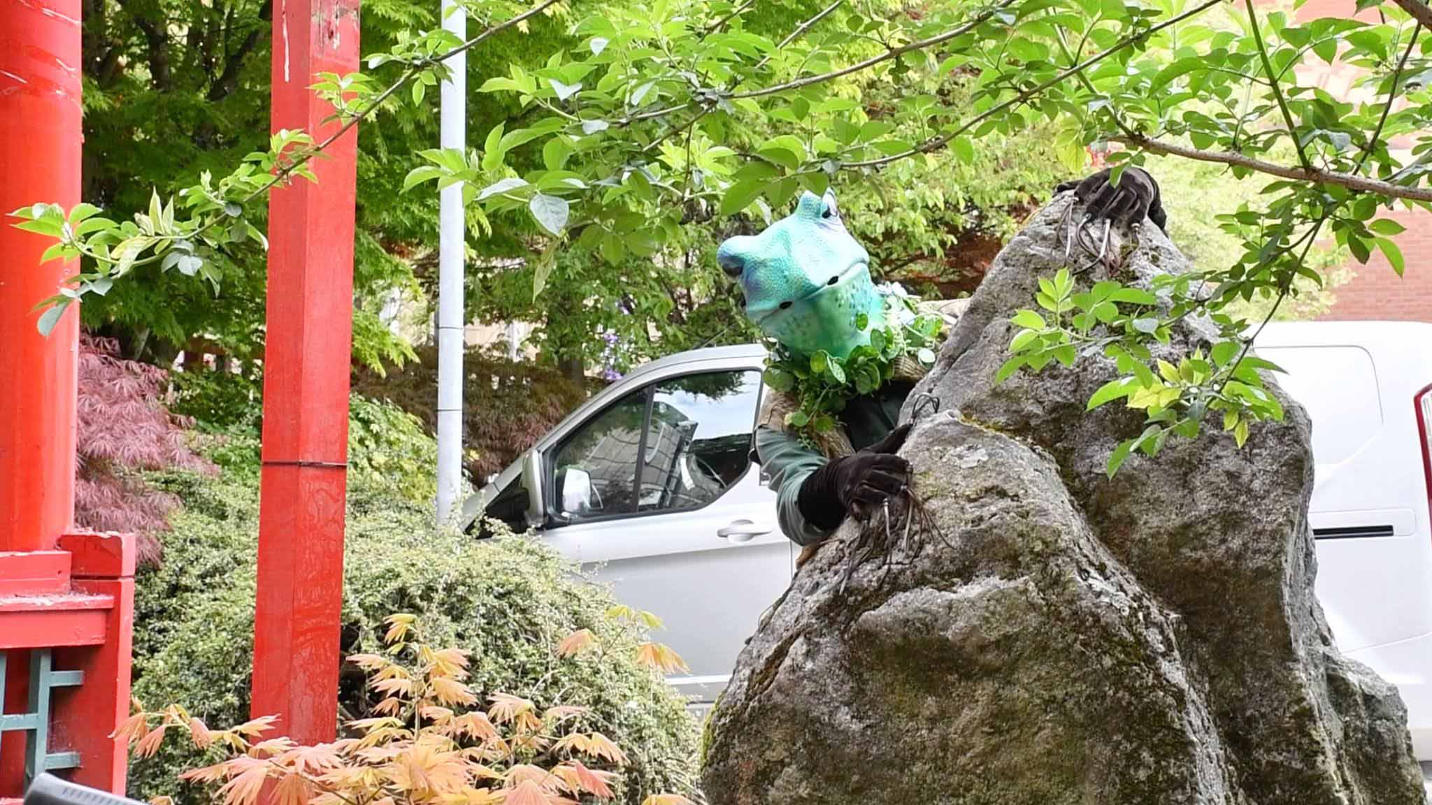 A man dressed as a frog leant against a tree