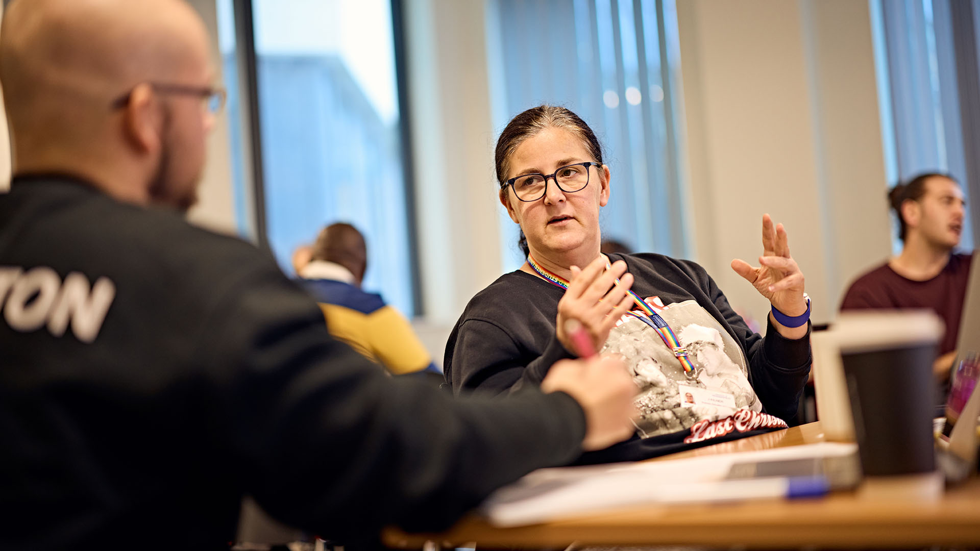 Teacher is in focus and is talking with a student