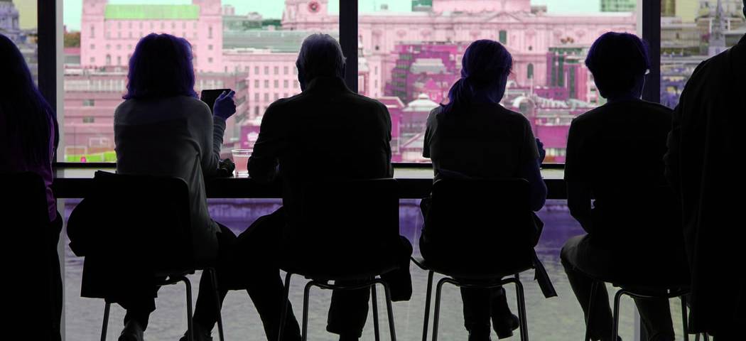 People sitting at barstools in front of a window