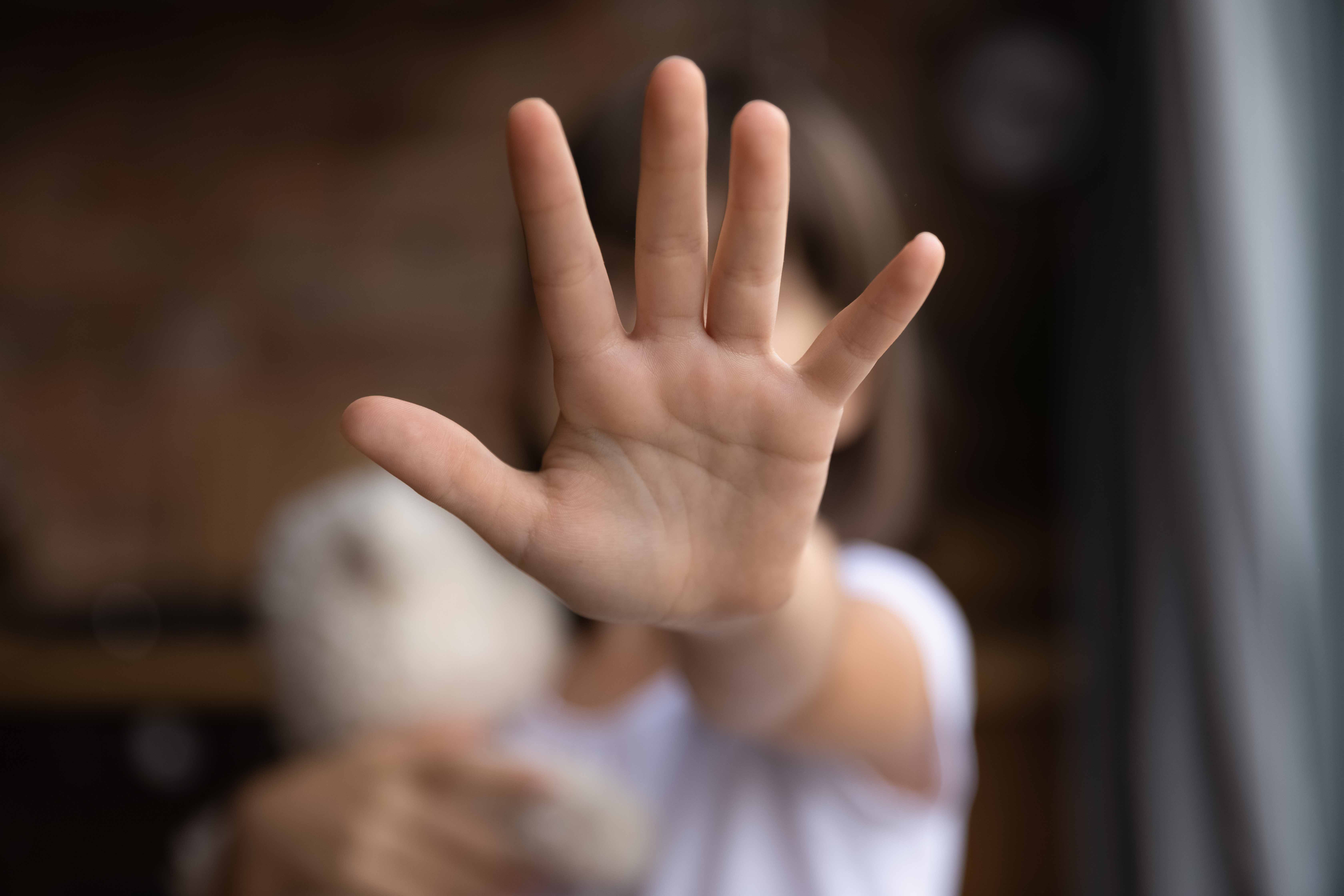 Young girl holding her hand towards the camera, as if to signal stop/no more