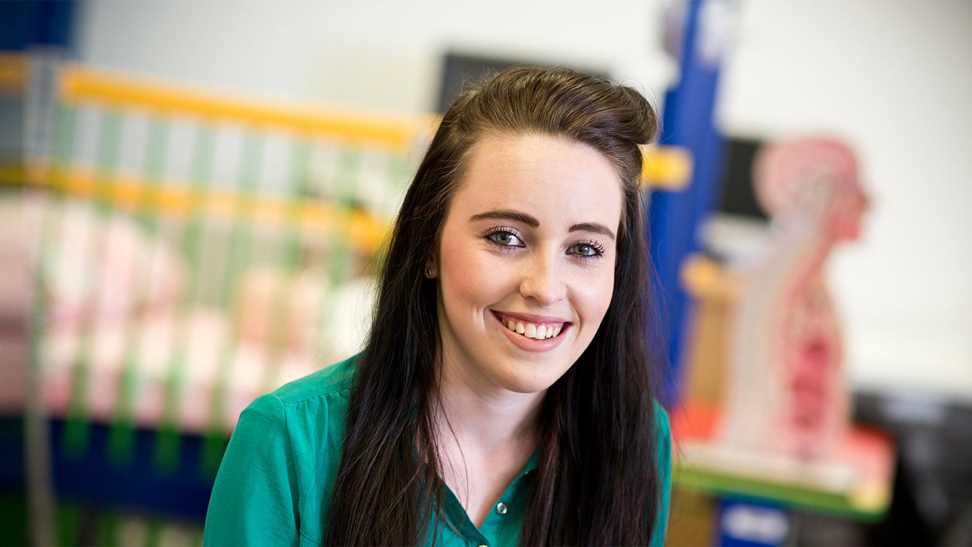 Human and Health student Emma Hogen smiling with healthcare objects in the background