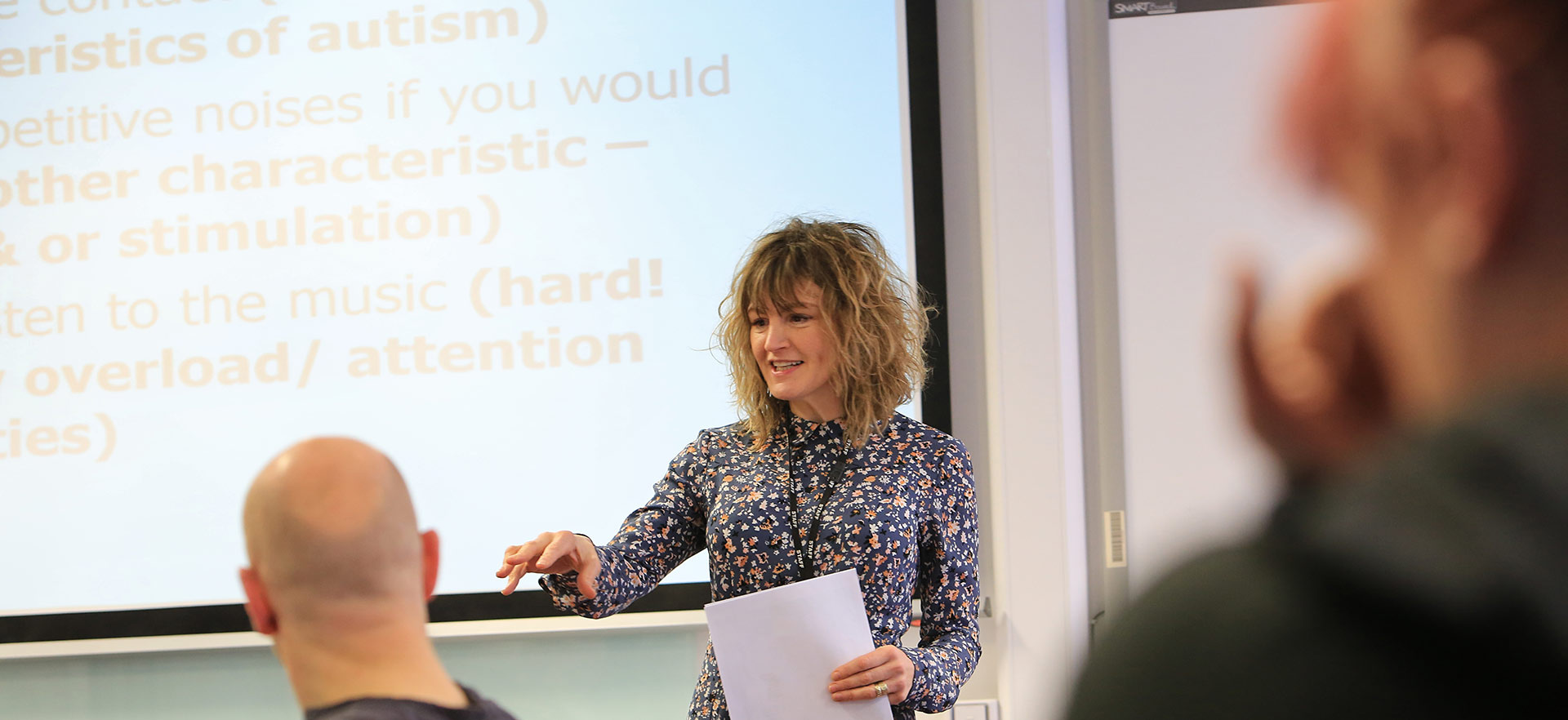 A female trainer delivering a training session in a classroom.