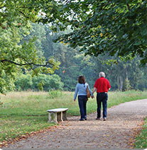 Thumbnail - Couple walking through a park holding hands.